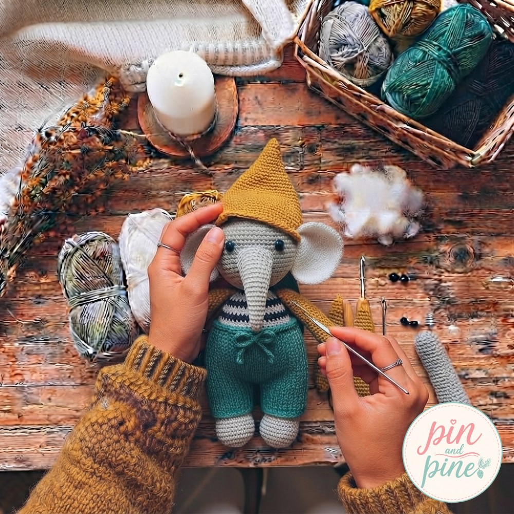 Teal drawstring pants tied on the crochet elephant amigurumi with mustard hat placed before securing