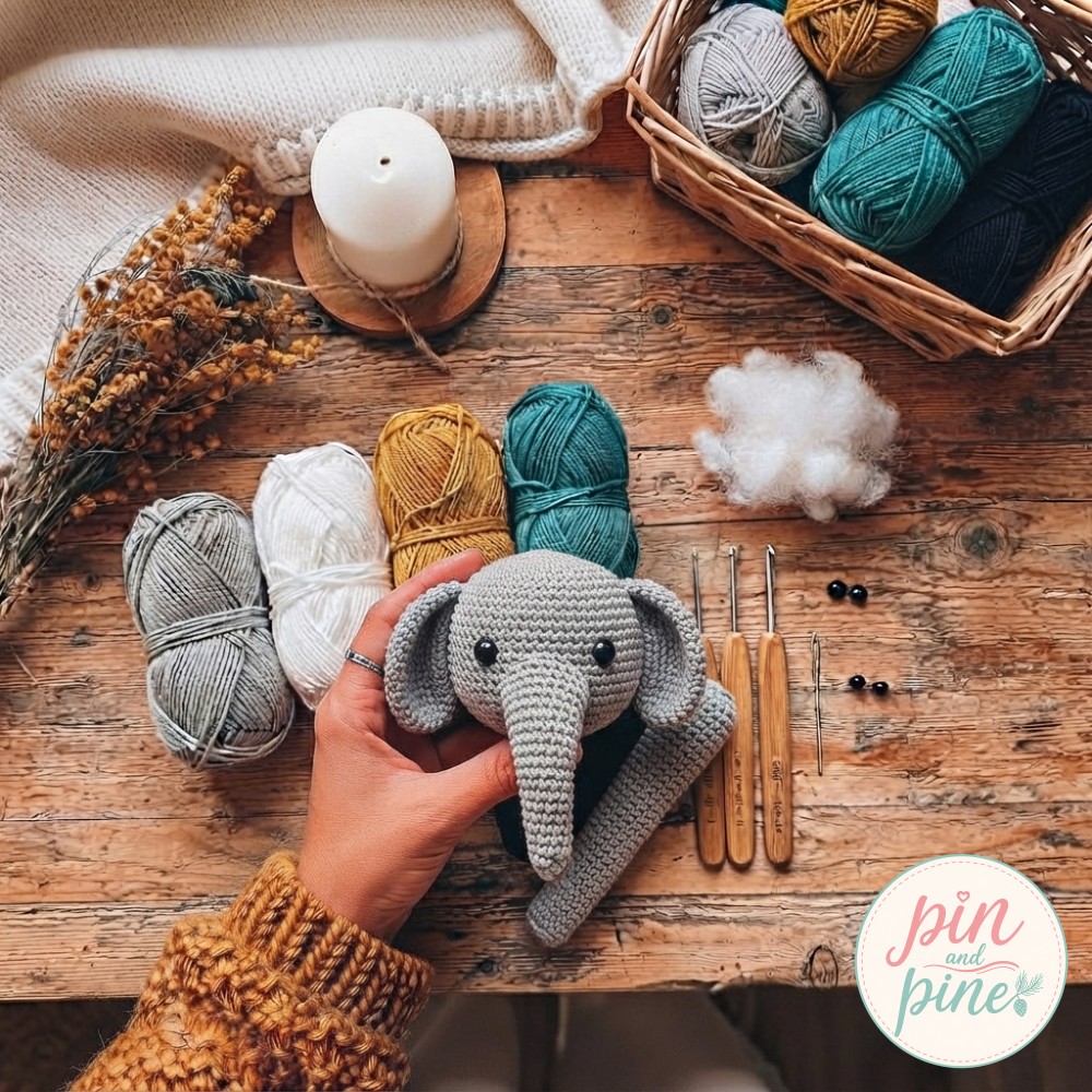 Finished grey head of the crochet elephant amigurumi with safety eyes and a separate crocheted trunk piece